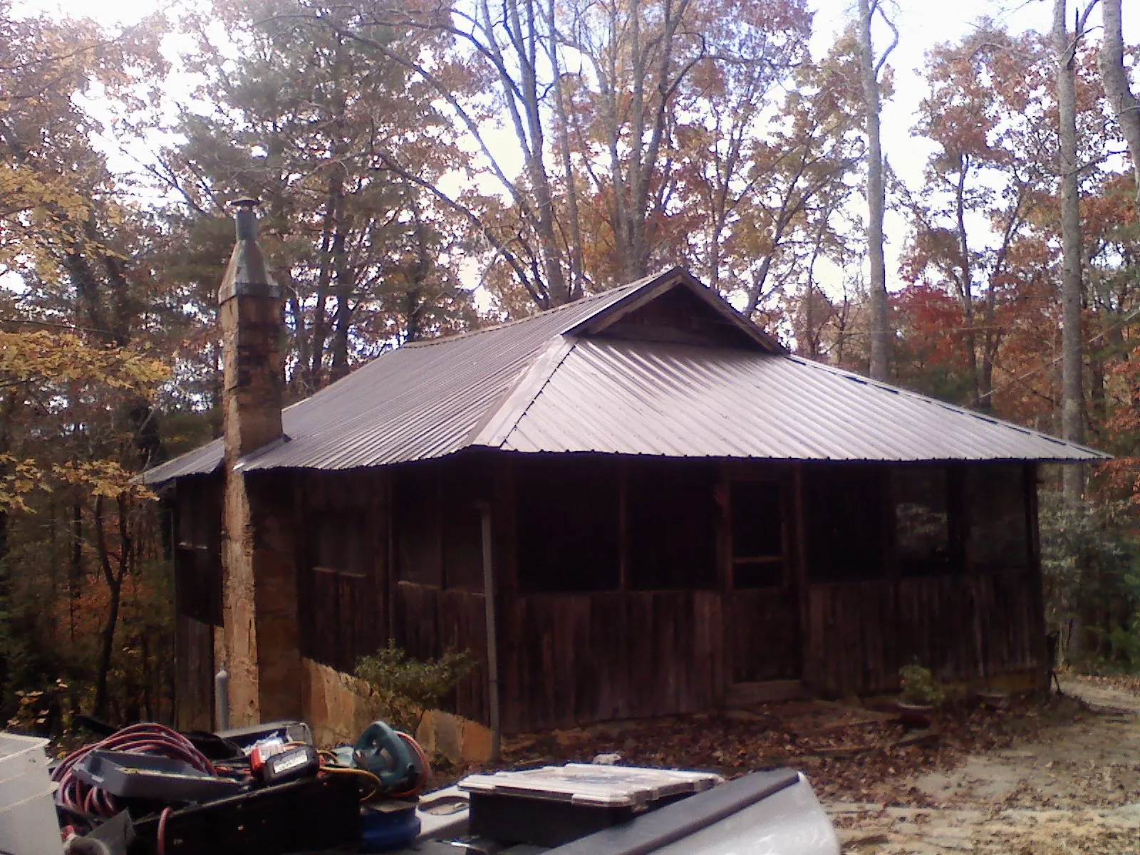 Brown metal hip roof on an old cabin with a stone chimney in Plymouth