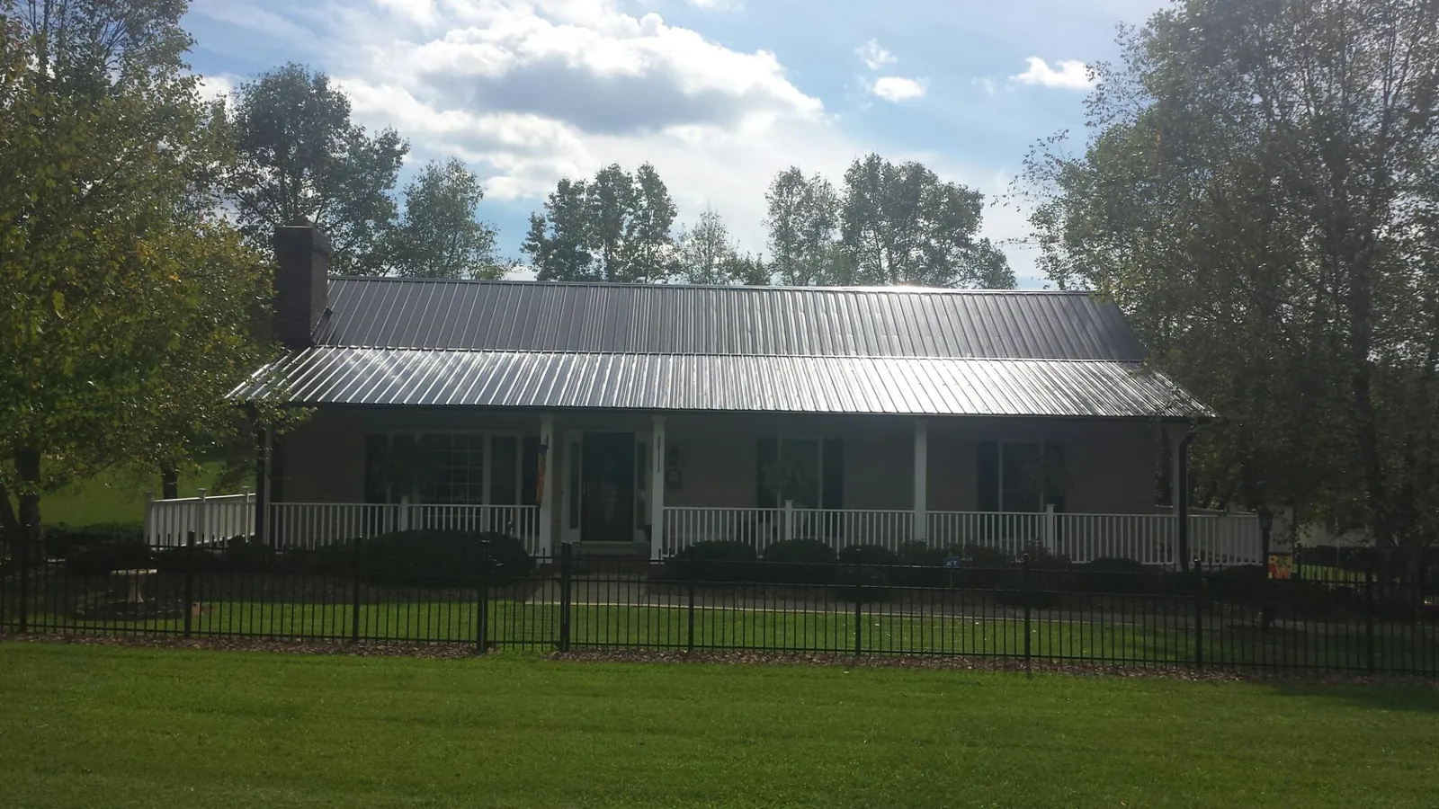 Gray metal roof on a brick ranch with a full width front porch — Gutter Guard Installation work by our crew in Plymouth